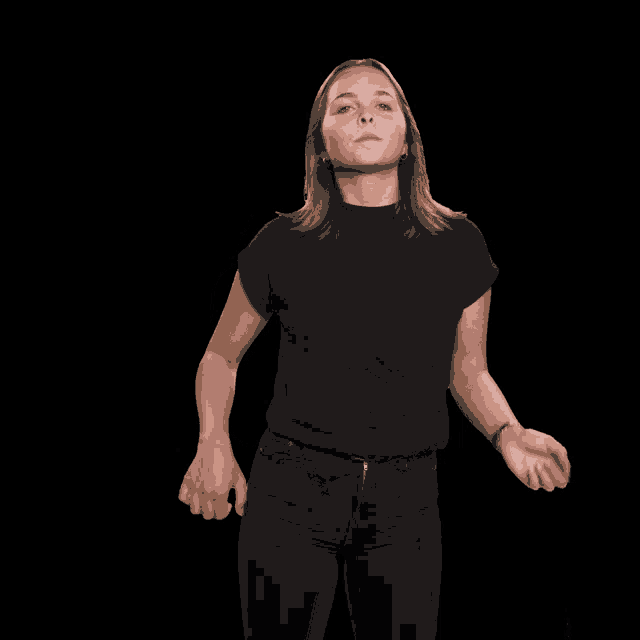 a woman in a black shirt and black jeans is standing with her arms outstretched