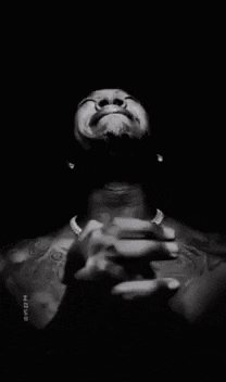 a man without a shirt is praying with his hands folded in front of his face .