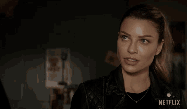 a woman wearing a black leather jacket with netflix written on the bottom right