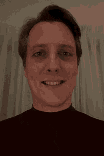 a man is smiling and giving a thumbs up with his hand