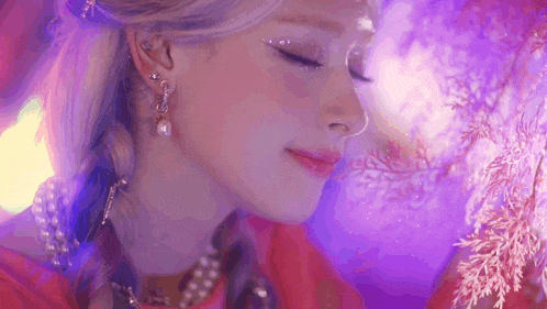 a close up of a woman 's face with purple lights behind her and a purple background .
