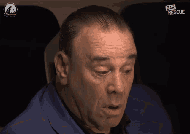 a man sitting in a car with a paramount logo on the bottom right