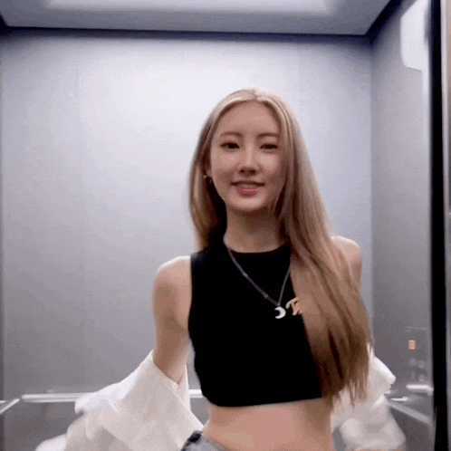 a woman in an elevator wearing a black crop top