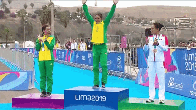 three women standing on a podium with the year lima 2019 on it