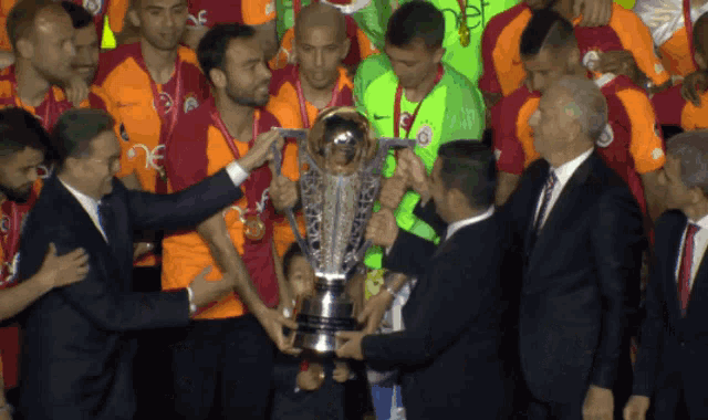 a group of men are holding a trophy and one of them is wearing a shirt that says ' ec ' on it