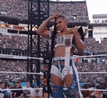 a woman is standing in a wrestling ring with a championship belt around her neck .