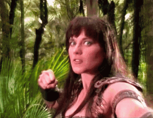 a woman in a snake costume is pointing at the camera in the woods