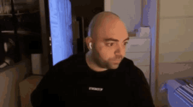 a bald man is sitting in front of a computer screen .