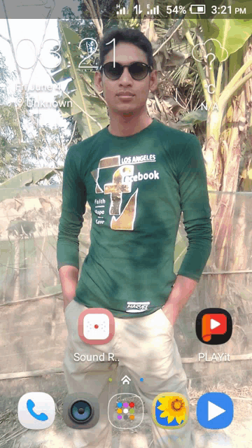 a man wearing a los angeles facebook shirt stands in front of a phone screen
