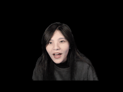 a woman making a heart shape with her hands on a black background