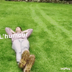 a woman is laying on the grass with her feet up and the words humour written above her