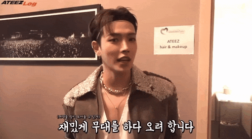 a man standing in front of a sign that says " ateez hair & makeup "