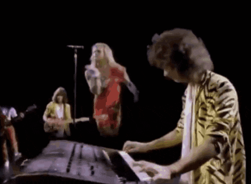 a man in a tiger print shirt is playing a keyboard in front of a group of musicians .