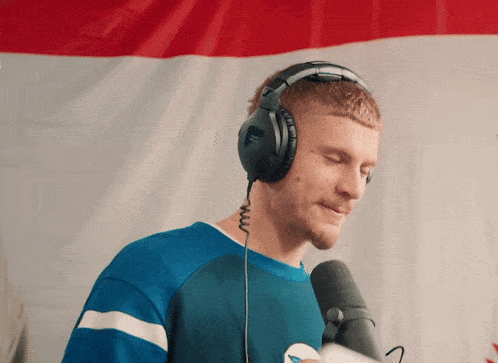 a man wearing headphones stands in front of a microphone with his eyes closed