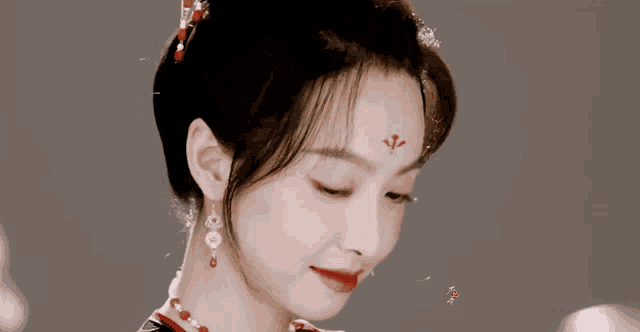 a woman with a red flower on her forehead is smiling