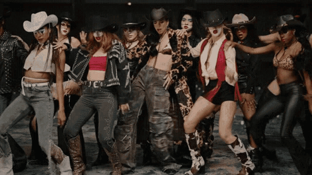 a group of women dressed in cowboy hats are dancing together