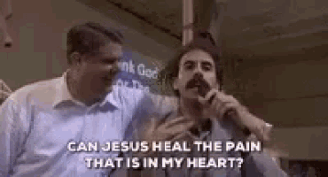 a man with a mustache is singing into a microphone while another man holds his arm around him .