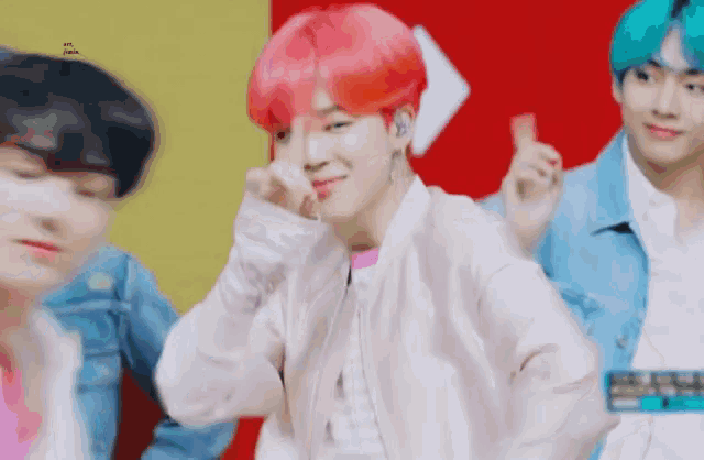 a man with pink hair is making a heart with his finger