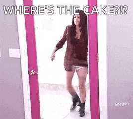 a woman is standing in a doorway with the words `` where 's the cake ? '' written on the door .