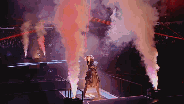 a woman stands on a stage in front of smoke coming out of the ceiling