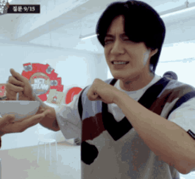 a man holds a bowl in front of a nct dream sign