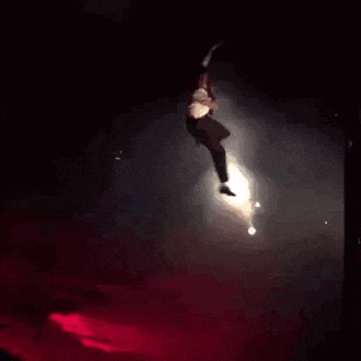 a man is falling through the air on a stage in the dark .
