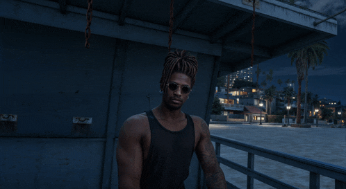 a man wearing sunglasses and a black tank top is standing on a pier at night