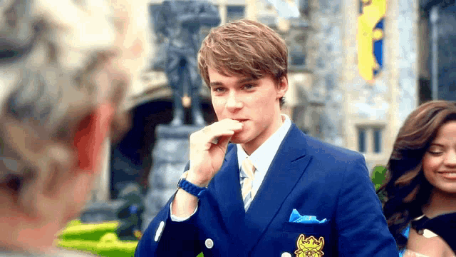 a man in a blue suit with a lion on his pocket square