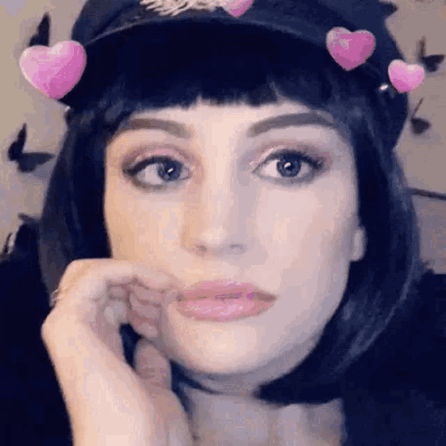 a woman wearing a police hat and a wig with pink hearts on her head is making a funny face .