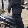a man in a black jacket is riding a motorcycle on a dirt road .