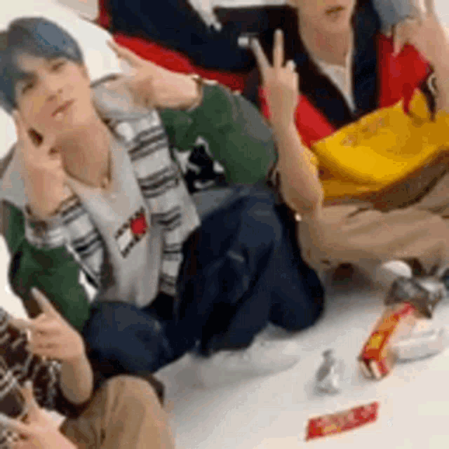 a group of people are sitting on the floor with their hands in the air giving the middle finger .