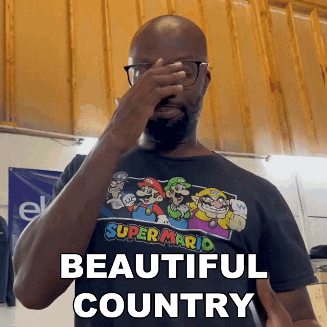 a man wearing a super mario shirt covers his face with his hand