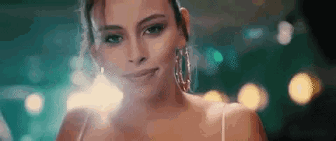 a close up of a woman wearing hoop earrings and a white top .
