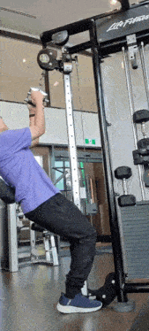 a man in a purple shirt is doing exercises on a life fitness machine