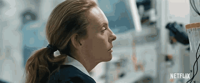a woman in a ponytail is looking at a computer screen in a lab .