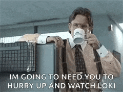 a man in a suit and tie is drinking a cup of coffee while leaning against a cubicle .