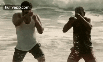 two men are standing next to each other on a beach .