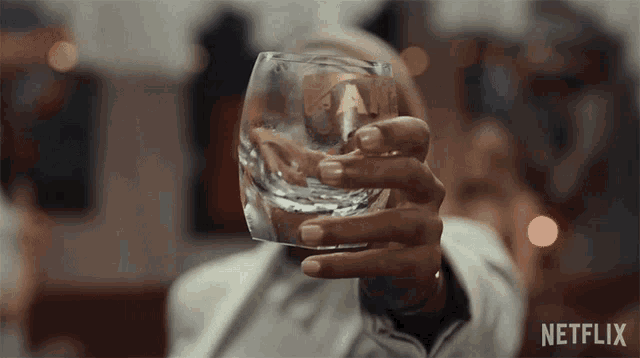 a person is holding a glass with a netflix logo on the bottom