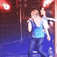 a woman is singing into a microphone while standing on a stage .