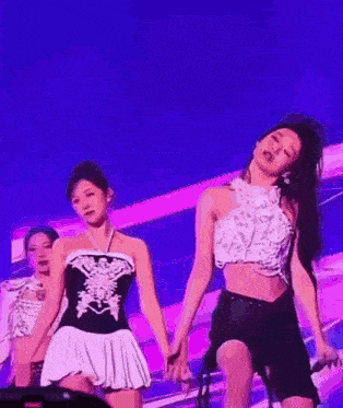 a group of women are dancing on a stage in front of a blue and purple background .