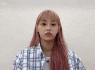 a young woman with pink hair is wearing a plaid shirt and making a funny face .