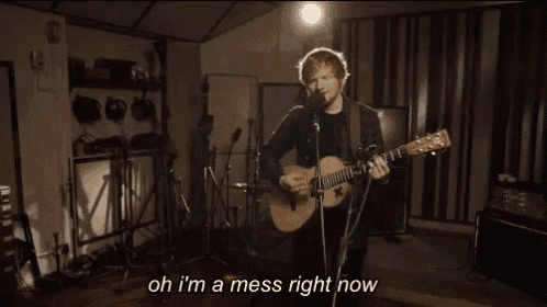 a man playing a guitar and singing into a microphone with the words " oh i 'm a mess right now " below him