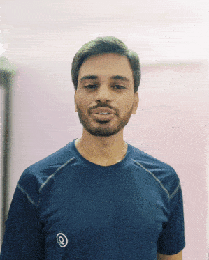 a man with a beard is wearing a blue shirt with the letter q on the front