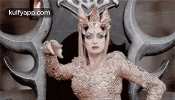 a woman in a costume is sitting on a throne with horns on her head .