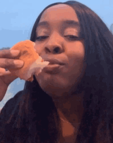 a woman is eating a sandwich with her mouth open .