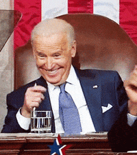 a man in a suit and tie is smiling while holding a glass