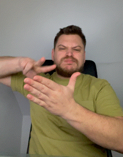a man in a green shirt is clapping his hands in front of his face