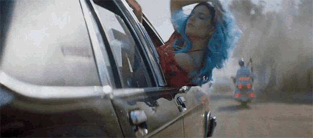 a woman with blue hair is sitting in a car .