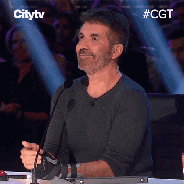 a man sitting in front of a microphone with a citytv logo above him