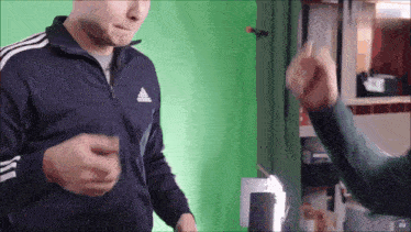 a man wearing an adidas jacket is giving a fist bump